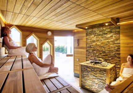 Drei sitzende Gäste in der Saunakabine - Kräutersauna im Classic-Saunabereich Drei sitzende Gäste in der Saunakabine - Kräutersauna im Classic-Saunabereich