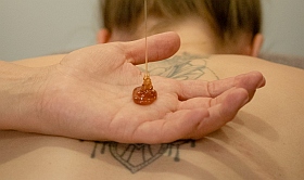 Massaeur lässt Honig in seine Handfläche fließen Massaeur lässt Honig in seine Handfläche fließen