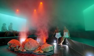 Vier Gäste sitzen auf der Steinbank, Wasserdampf steigt auf - SteinBad